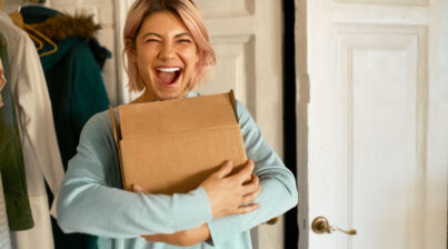 Uma jovem feliz segurando um caixa de papelão.