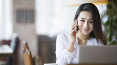 Uma mulher numa mesa de trabalho fazendo uma ligação telefônica para cobrar um cliente