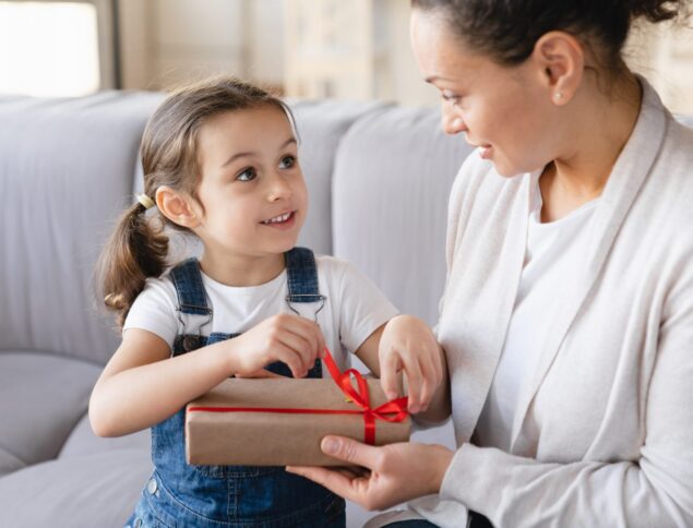 Uma criança entregando um presente para uma mulher, simbolizando o Dia das Mães
