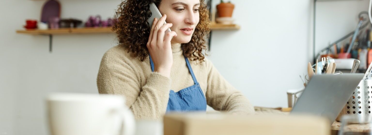 Uma empreendedora falando ao telefone no seu escritório.