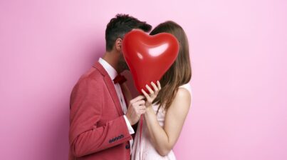 Um casal atrás de um balão de coração
