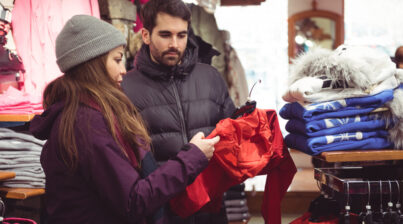 Casal escolhendo roupas de inverno dentro de uma loja