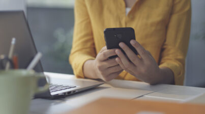 Mulher sentada na mesa no escritório enviando mensagens com seu smartphone