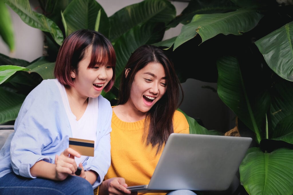 Duas mulheres asiáticas empolgadas com promoção de vendas na loja online